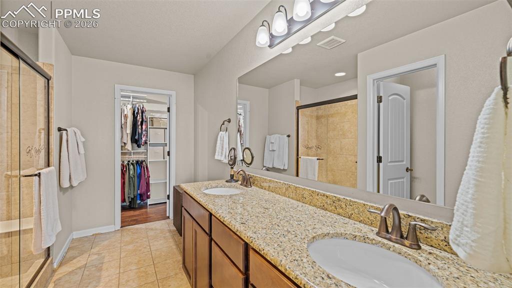 Image 16 of 27: Bathroom featuring a dual vanity with a speckled countertop, integrated sin