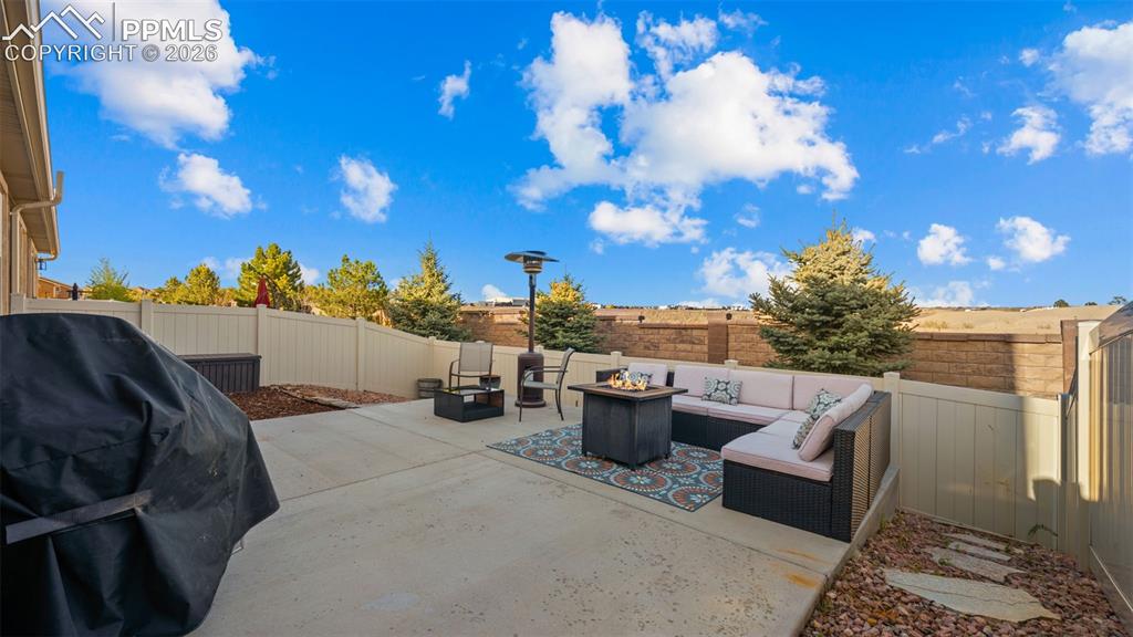Image 24 of 27: Expansive concrete patio area, featuring a full privacy fence, integrated l