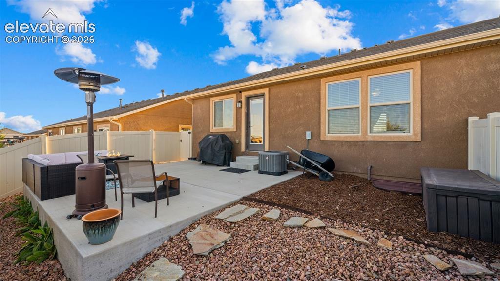 Image 25 of 27: Concrete patio with stucco exterior, featuring a private fence, multiple wi