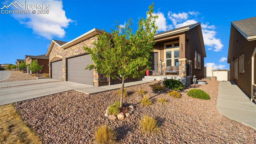 Image 3 of 27: Exterior featuring a stone facade, a covered front porch, and a two-car gar