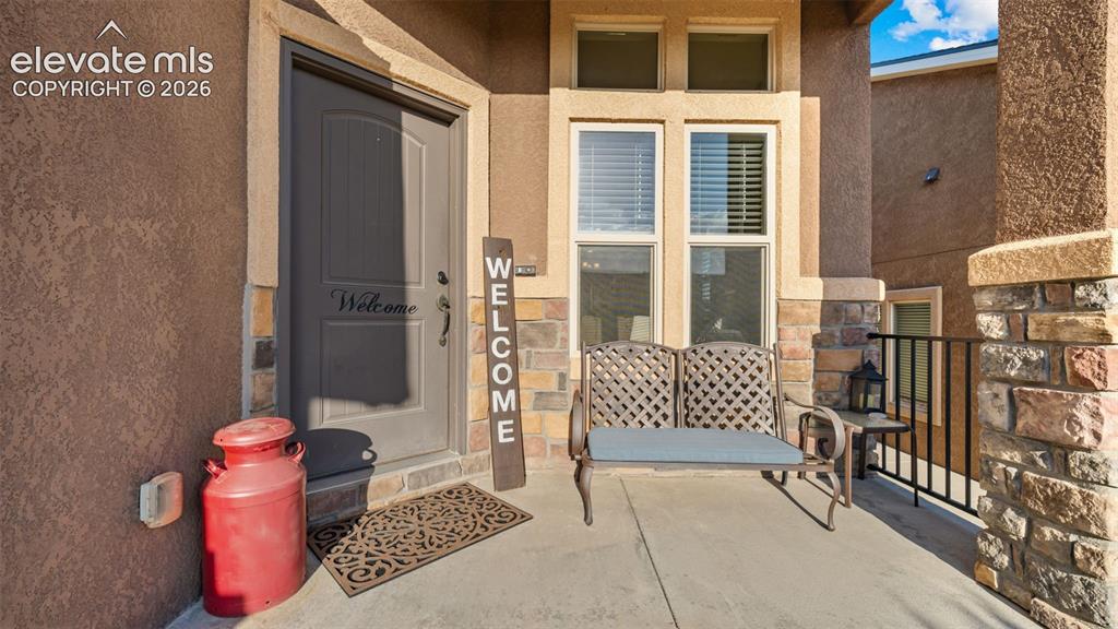 Image 3 of 27: Inviting front porch featuring a paneled entry door, stucco exterior, and s