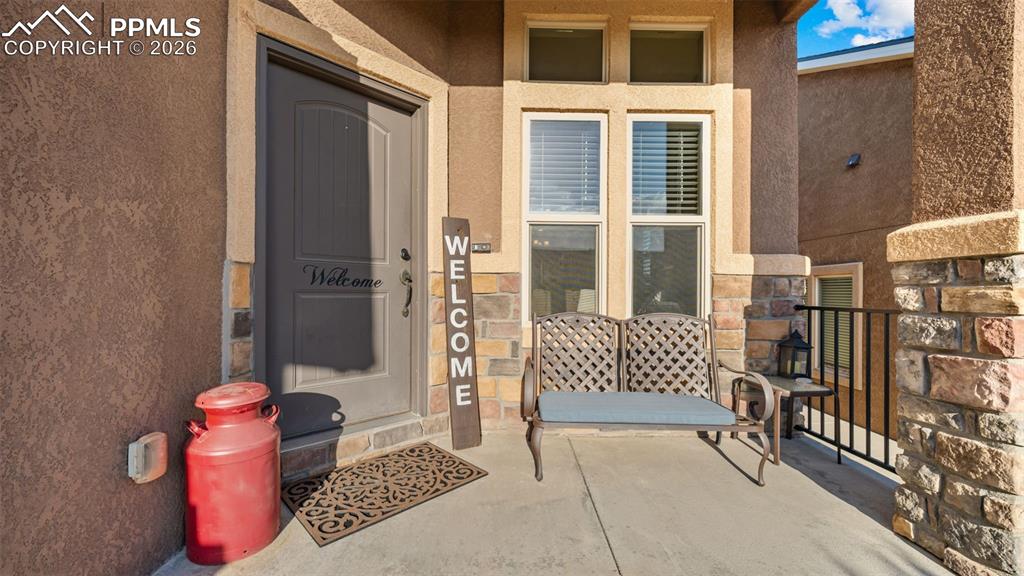 Image 4 of 27: Inviting front porch featuring a paneled entry door, stucco exterior, and s