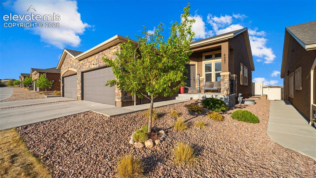 Image 4 of 27: Exterior featuring a stone facade, a covered front porch, and a two-car gar