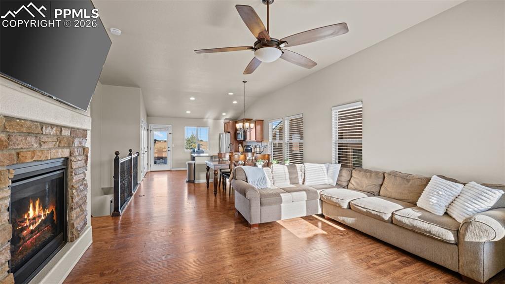 Image 5 of 27: Spacious living area featuring wood-finish flooring, a stone-clad fireplace