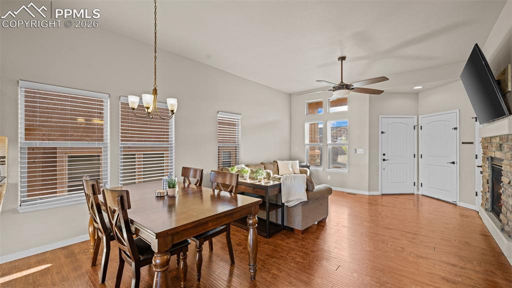 Image 9 of 27: Open-concept living area featuring wood-finish flooring, a stone-faced fire