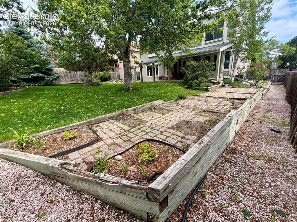 Image 12 of 49: Expansive backyard featuring a green lawn, mature trees, and a wooden retai
