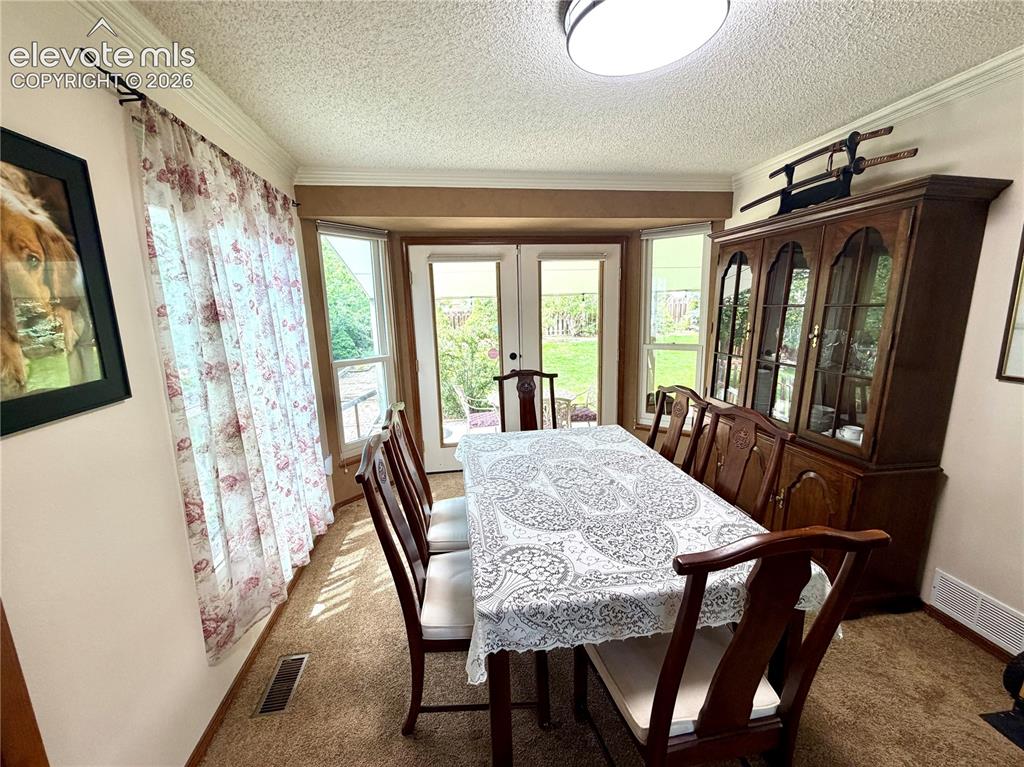 Image 18 of 49: Dining space featuring  windows, double patio doors, crown molding, and car