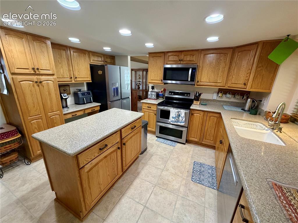 Image 23 of 49: Kitchen featuring wood-finish cabinetry, a large center island with a light