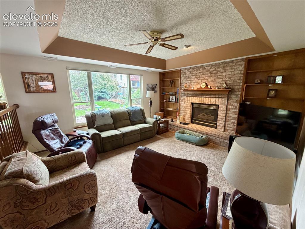 Image 24 of 49: Living area with a prominent brick-faced fireplace, flanked by built-in woo