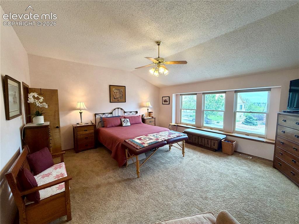 Image 25 of 49: Spacious room featuring vaulted ceilings, a ceiling fan with integrated lig