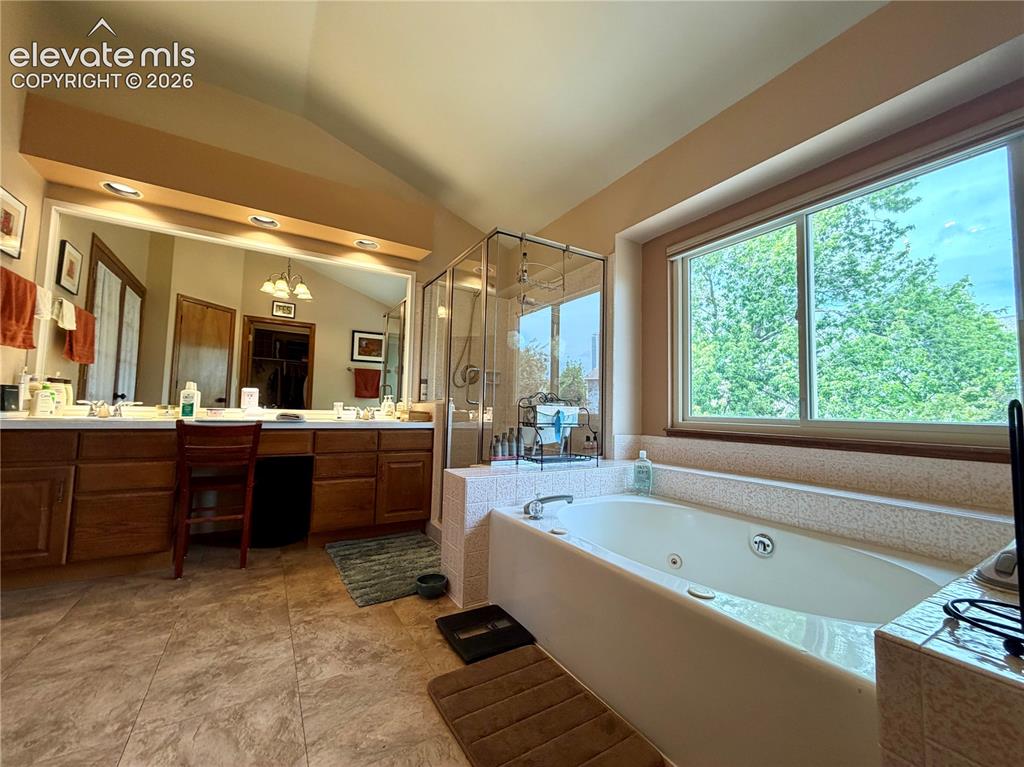 Image 33 of 49: Spacious bathroom featuring a built-in jetted tub, a separate glass-enclose