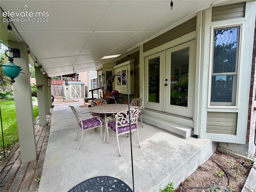 Image 6 of 49: Covered concrete back patio featuring exterior door with dual glass panels