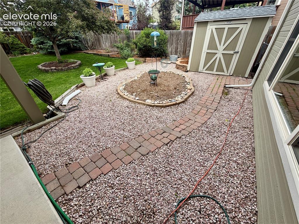Image 7 of 49: Spacious backyard featuring a decorative groundcover, a curving brick paver