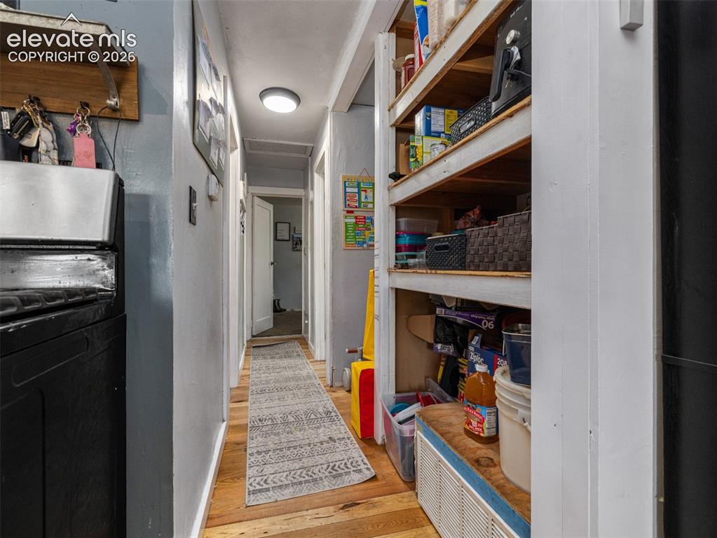 Image 10 of 26: Efficient galley-style hallway with wood-finish flooring, built-in shelving