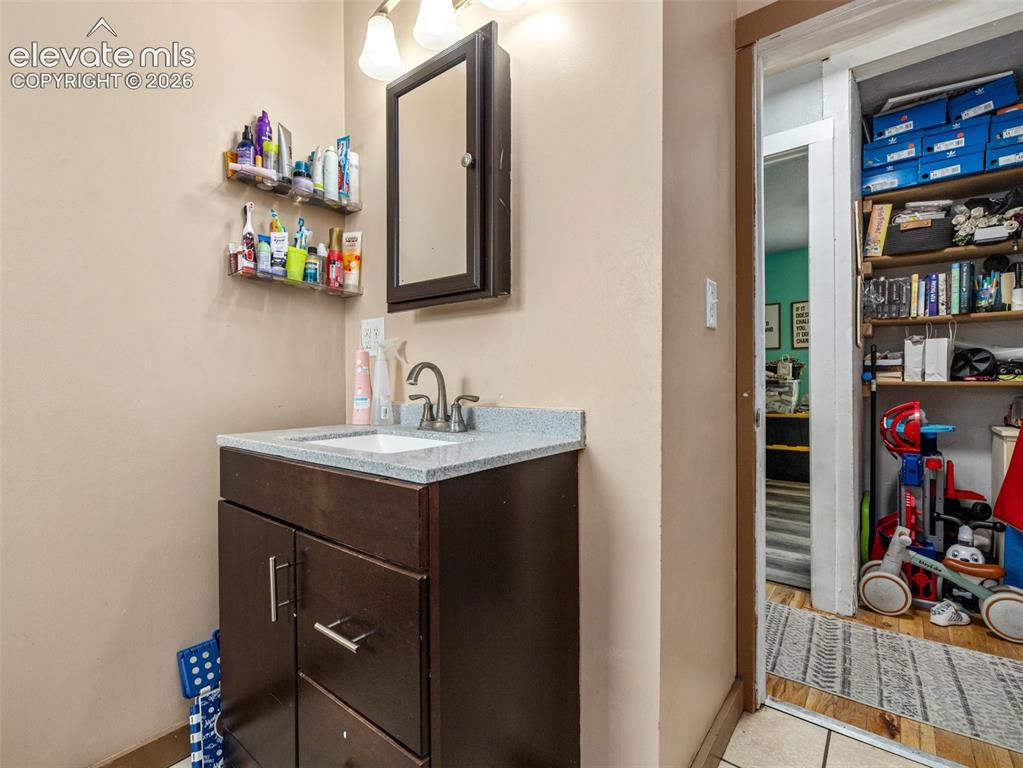 Image 18 of 26: Bathroom vanity with a gray granite-style countertop, integrated sink, and