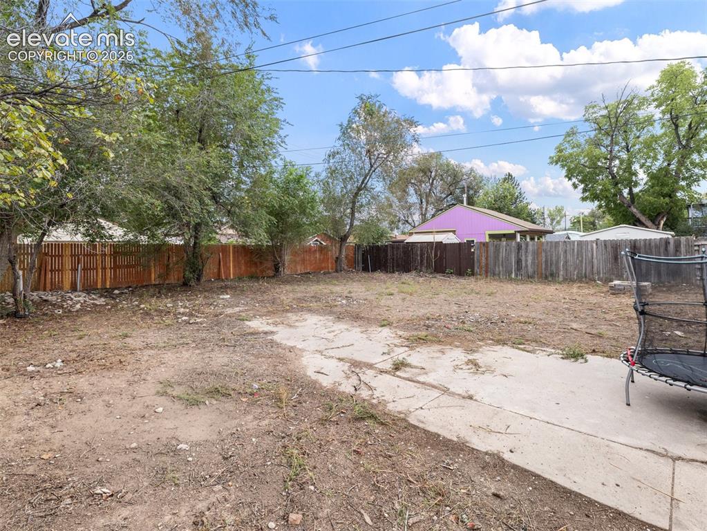 Image 22 of 26: Spacious outdoor area featuring a concrete patio, perimeter fencing, and ma