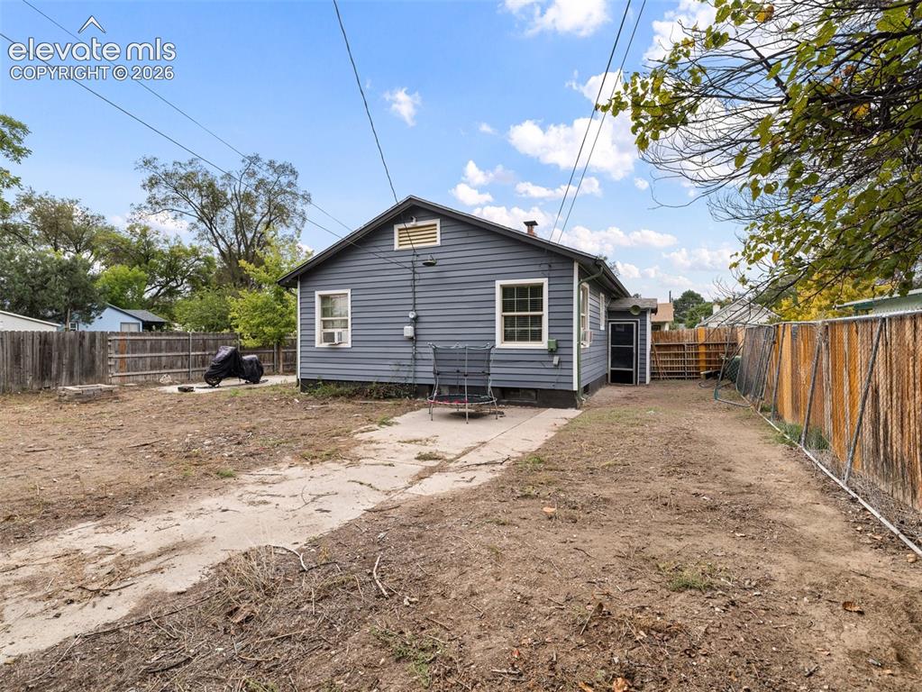 Image 24 of 26: Rear exterior featuring siding, white trim windows, and fenced perimeter