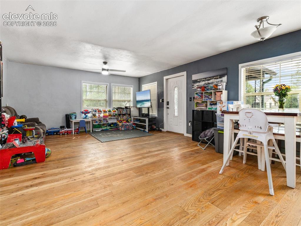 Image 5 of 26: Natural wood-finish flooring, multiple windows with blinds, a ceiling fan,