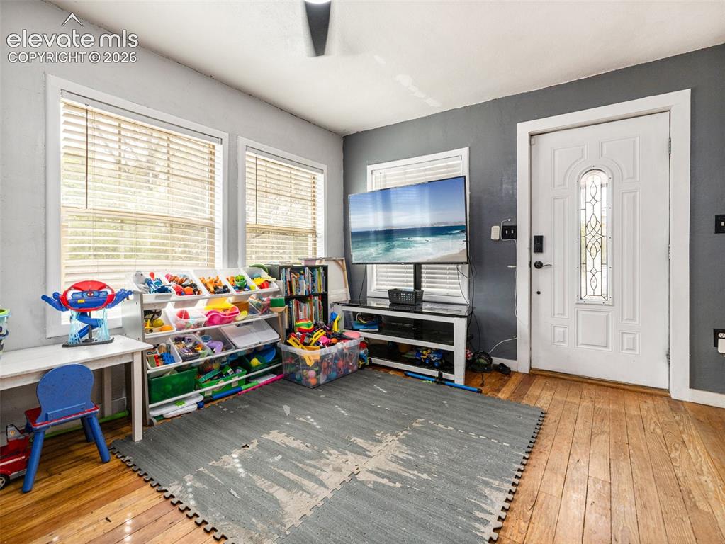 Image 7 of 26: Hardwood flooring, multiple windows with blinds, and a white paneled door w