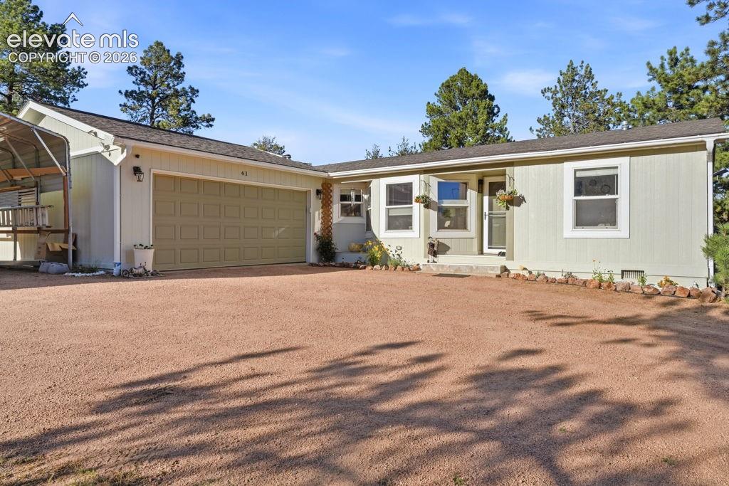 Caption: Attached two-car garage, gravel driveway, and light-colored siding
