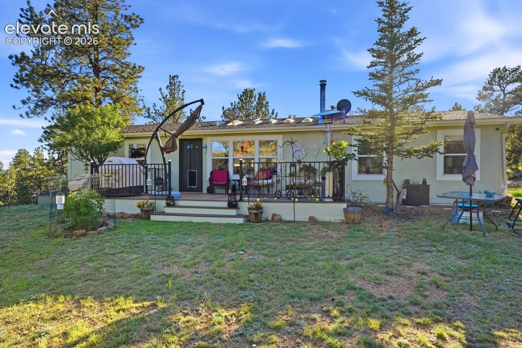 Image 10 of 50: Elevated rear deck with black metal railing, multiple windows, and a glass-