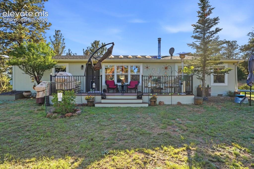 Image 12 of 50: Rear deck with exterior railings, multiple windows, and exterior sconce lig
