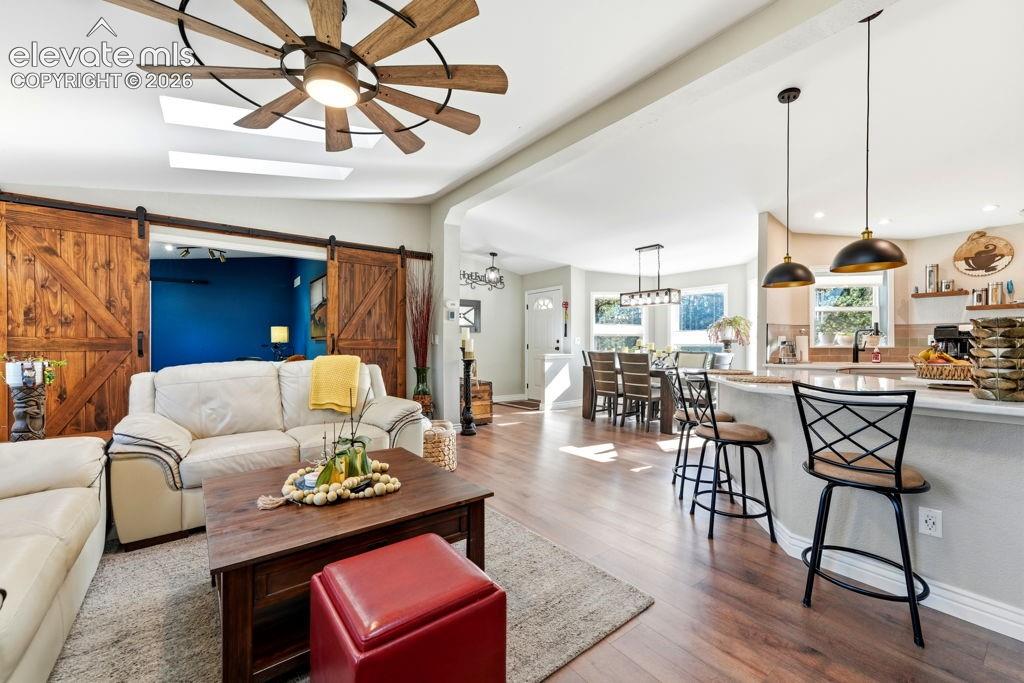 Image 21 of 50: Wood-finish flooring throughout, featuring a kitchen island with pendant li