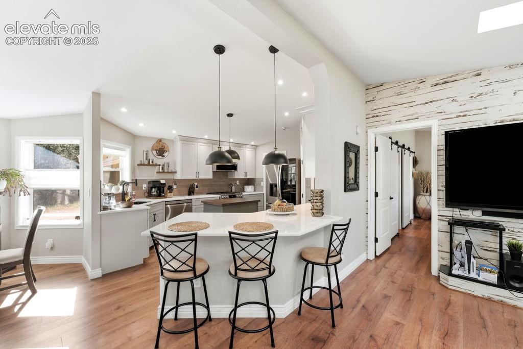 Image 23 of 50: Wood-finish flooring throughout, kitchen with light-toned cabinetry and sta