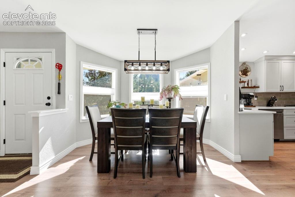 Image 25 of 50: Dining area with wood-finish flooring, a contemporary chandelier, and multi