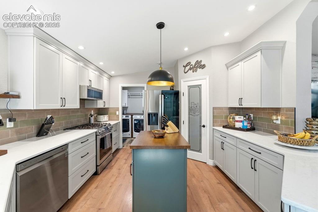 Image 26 of 50: Light wood-finish flooring with white cabinetry, stainless steel appliances