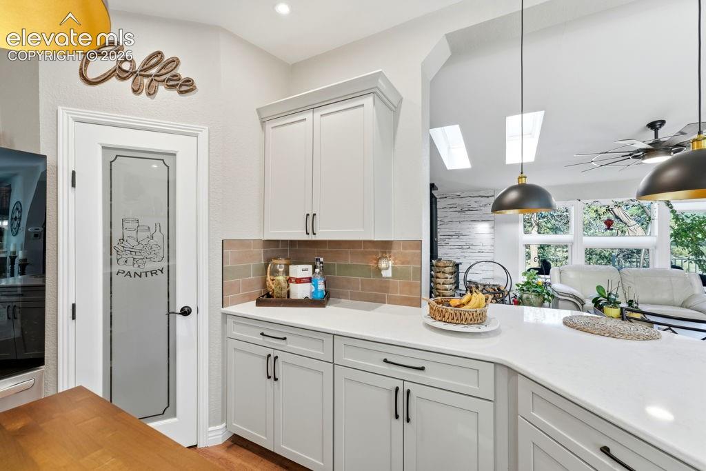 Image 28 of 50: White shaker-style cabinetry with dark hardware, solid surface countertops,