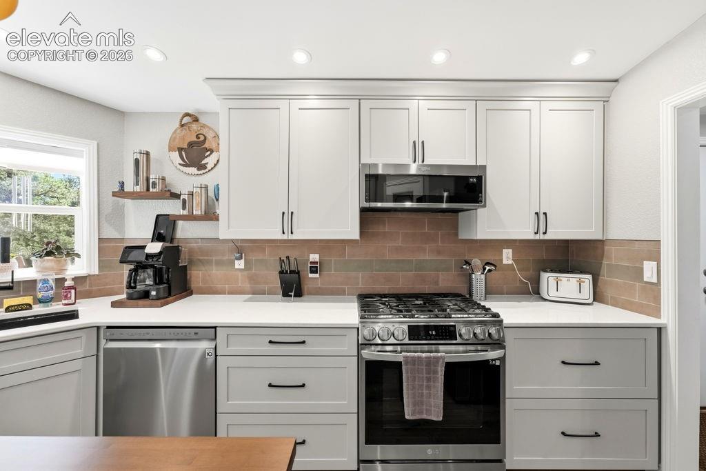Image 30 of 50: Light-toned cabinetry, white countertops, stainless steel appliances, and a