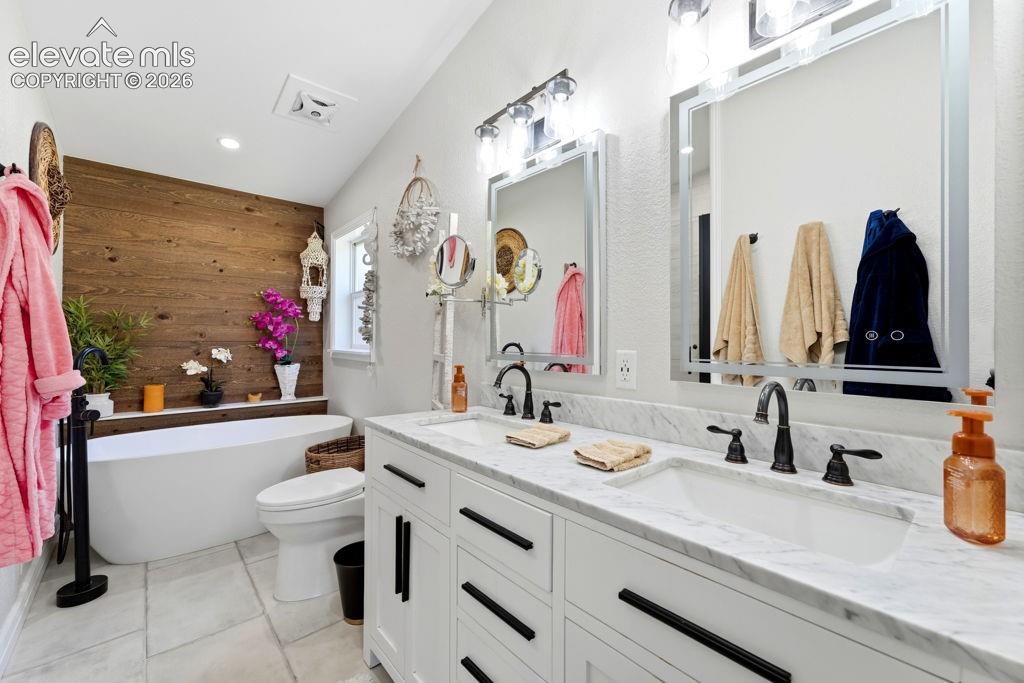 Image 36 of 50: Dual vanity with white cabinetry, marble-finish countertop, and integrated