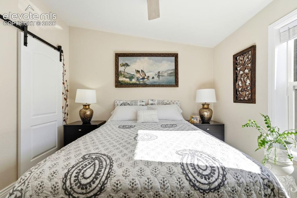 Image 41 of 50: Sliding barn door with black hardware, wall-mounted ceiling fan, and window