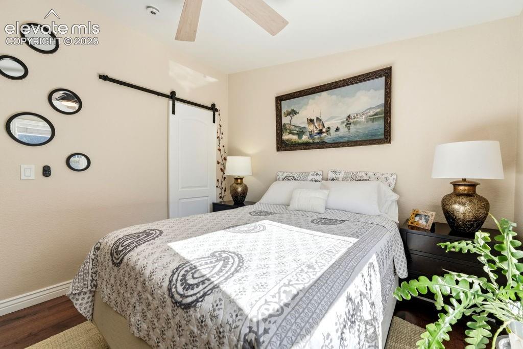 Image 43 of 50: Wood-finish flooring, ceiling fan, and a barn door entry
