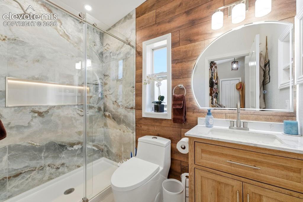 Image 44 of 50: Walk-in shower with natural stone-inspired tile and integrated niche, wood-