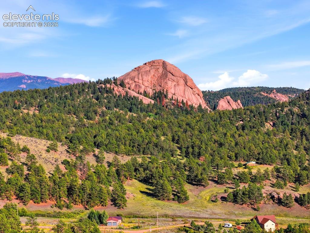 Image 48 of 50: Mountain landscape with a prominent red rock formation, extensive evergreen