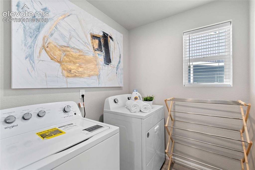 Image 11 of 25: Dedicated laundry area with light gray walls, a window featuring white blin