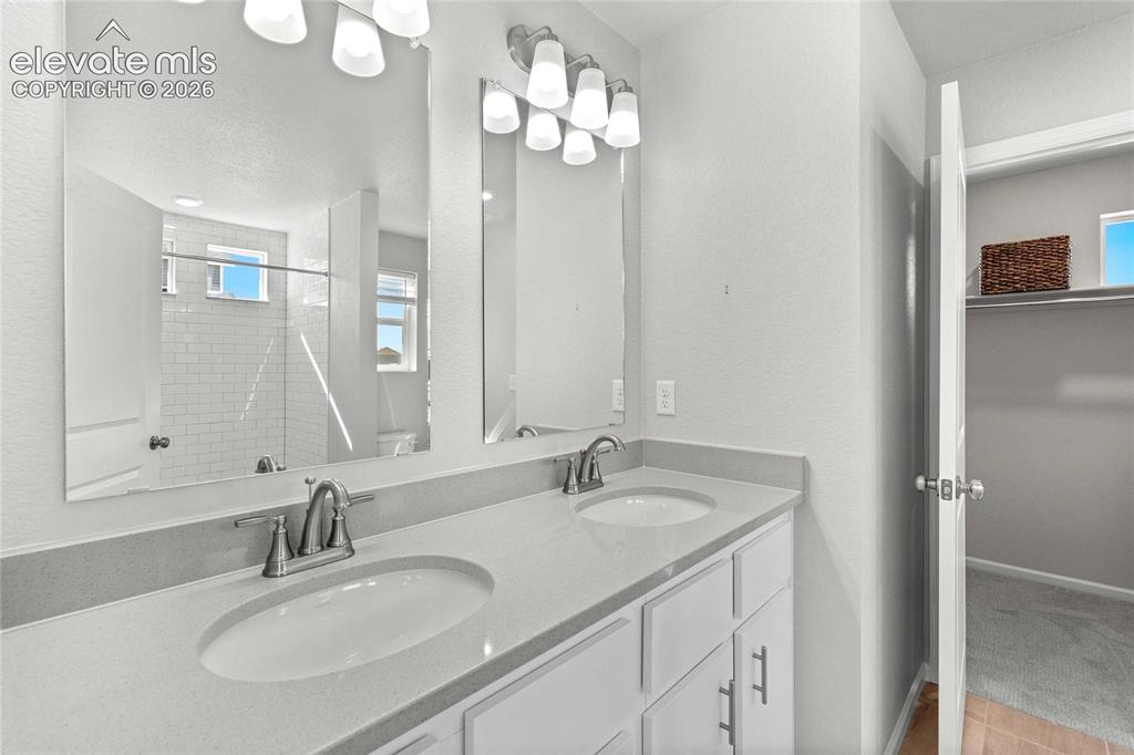 Image 14 of 25: Dual vanity with undermount sinks, light-toned countertop, and brushed nick