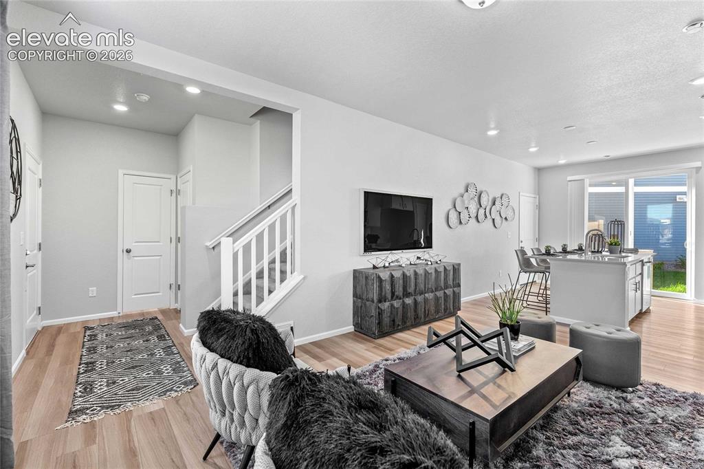 Image 4 of 25: Recessed lighting throughout, light wood-finish flooring, white painted sta