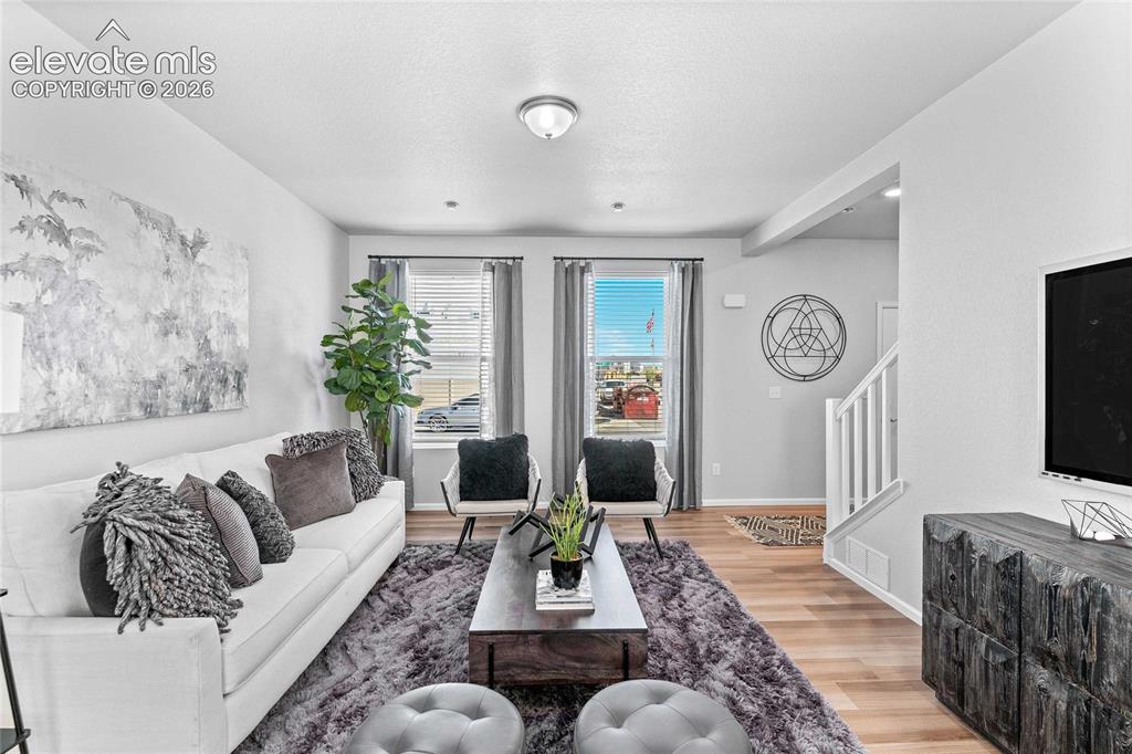 Image 5 of 25: Expansive living area with wood-finish flooring, two large windows, recesse