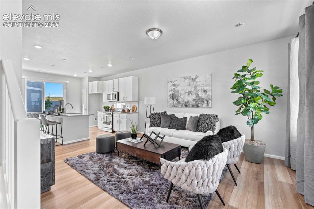 Image 6 of 25: Open-concept living area featuring light wood-finish flooring, recessed lig