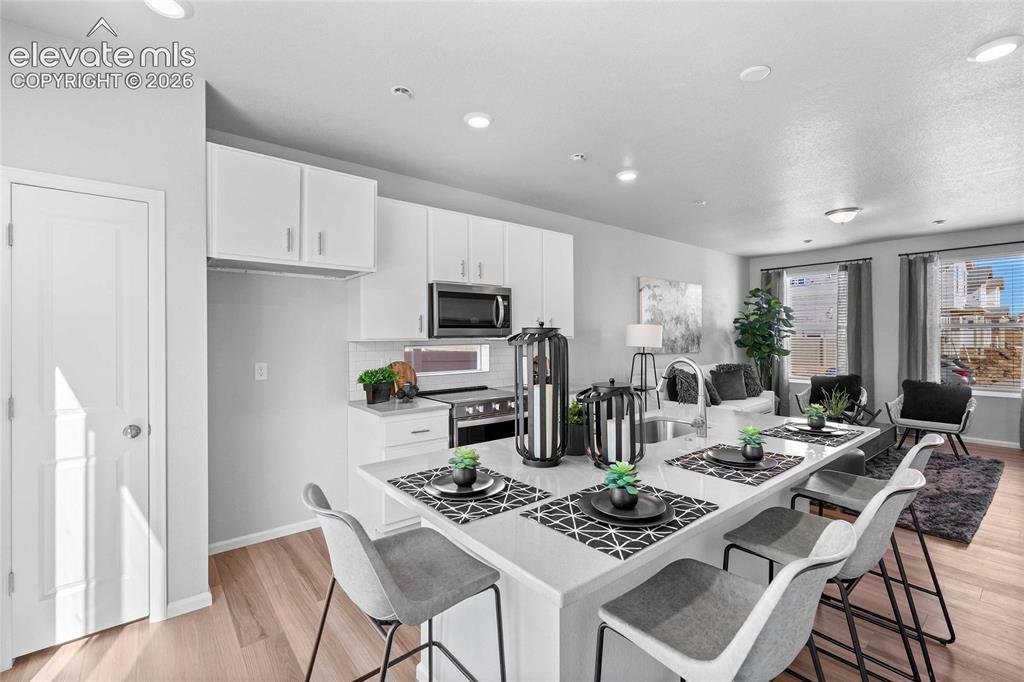 Image 8 of 25: Open-concept living space with wood-finish flooring, recessed lighting, and