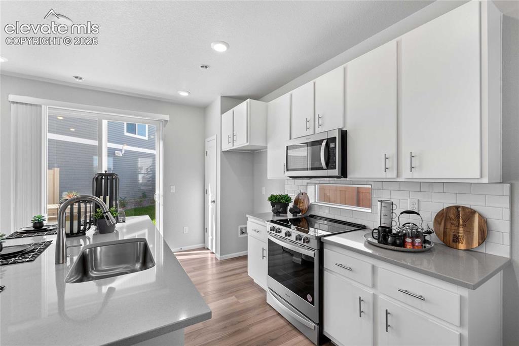 Image 9 of 25: Kitchen featuring light wood-finish flooring, white cabinetry, stainless st