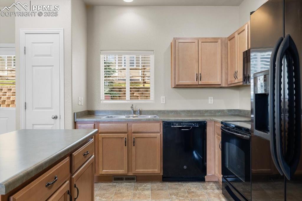 Image 11 of 42: Kitchen featuring black appliances and light brown cabinetry