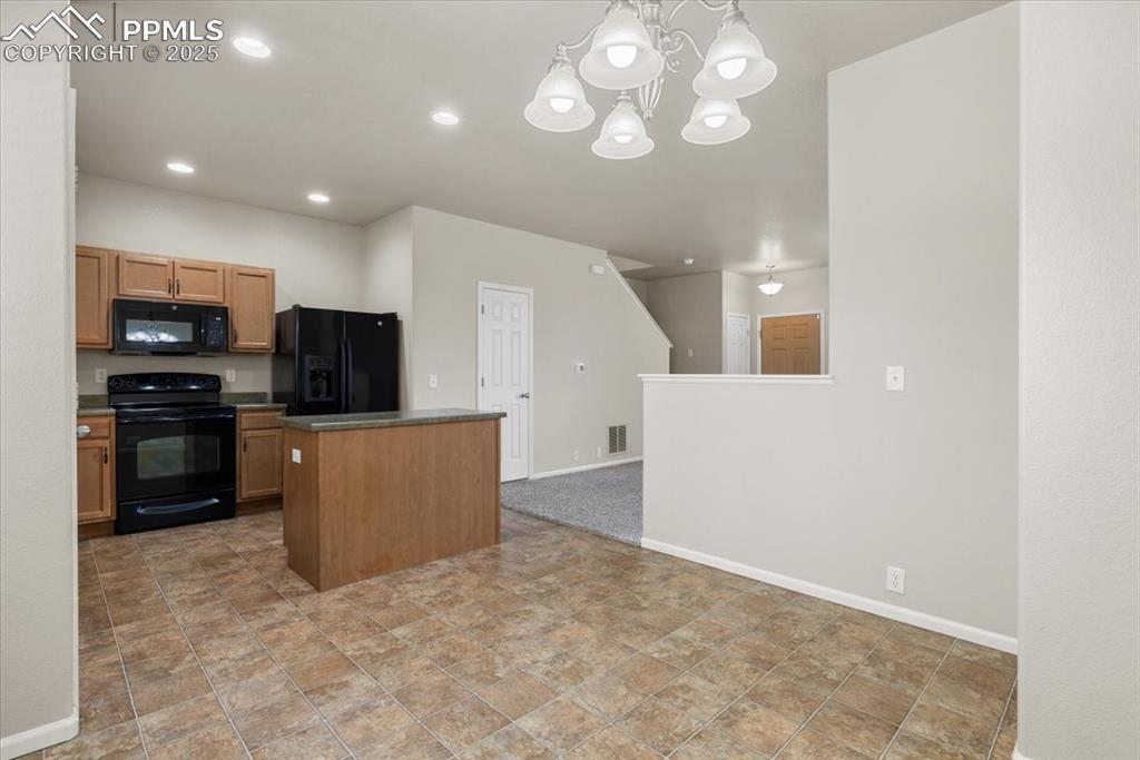 Image 14 of 42: Kitchen with black appliances, decorative light fixtures, a chandelier, rec