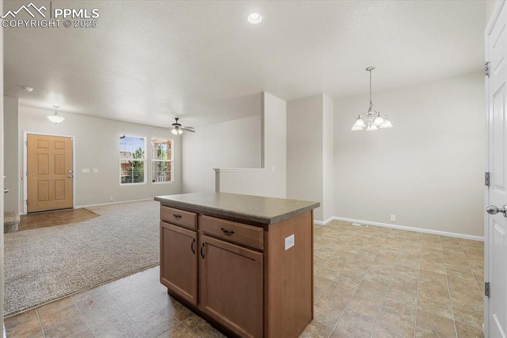 Image 15 of 42: Kitchen with open floor plan, dark countertops, pendant lighting, a center