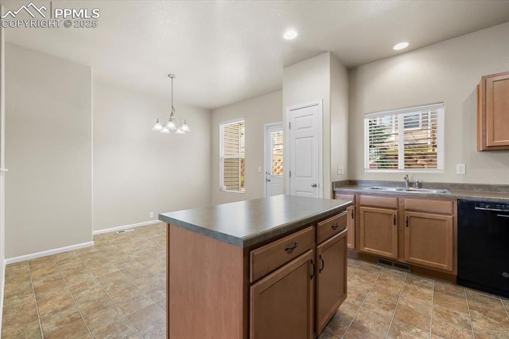 Image 16 of 42: Kitchen featuring dark countertops, dishwasher, decorative light fixtures,