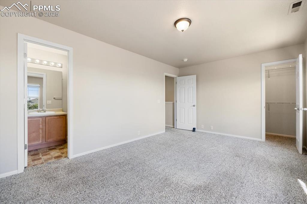 Image 23 of 42: Unfurnished bedroom with carpet, a walk in closet, and ensuite bathroom