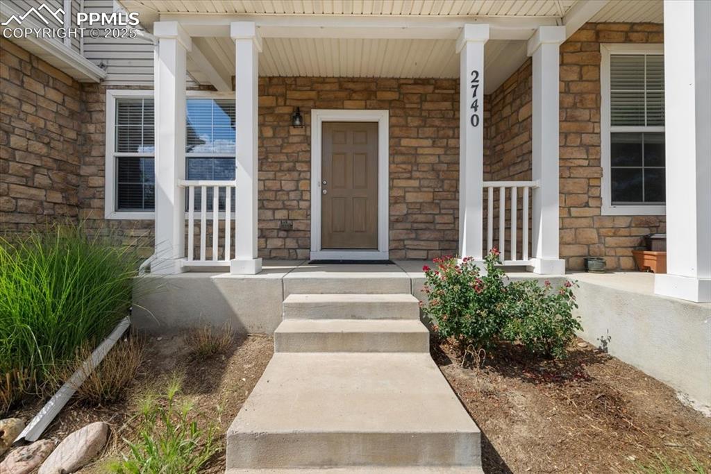 Image 3 of 42: Property entrance featuring stone siding and covered porch
